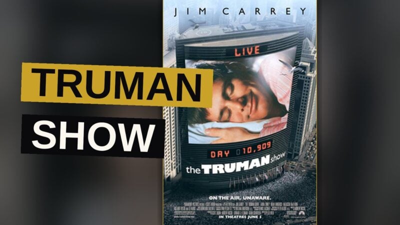 Jim Carrey as Truman Burbank stands before the painted sky wall of his artificial world, reaching out to touch it.