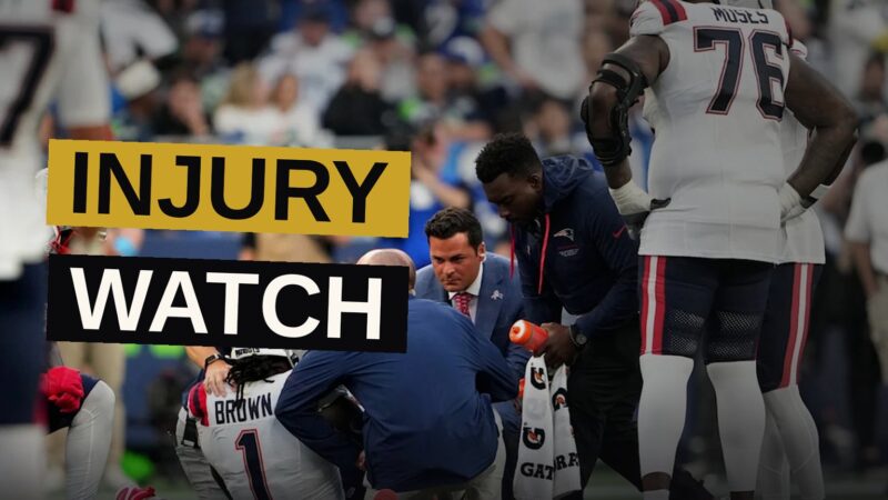 A New England Patriots wide receiver sits on the sideline wearing a walking boot after an ankle injury.