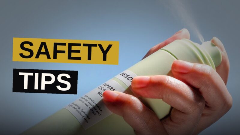A woman stands near a security camera and wasp spray inside her home.