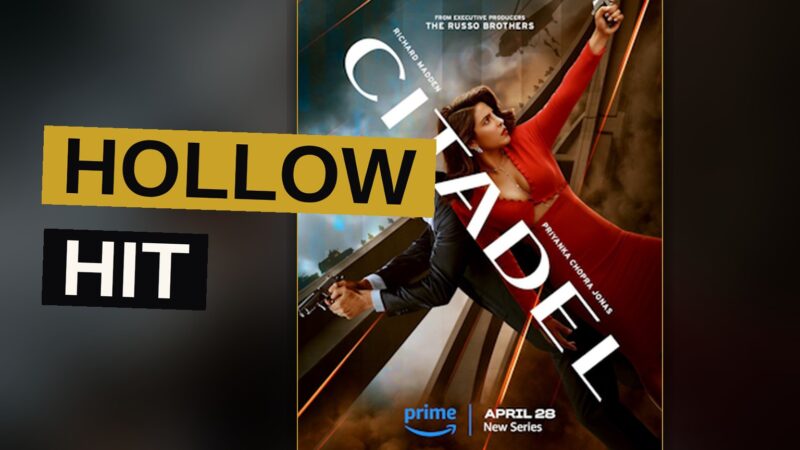 A spy balances atop a speeding train against a dusky city skyline in a tense action scene.