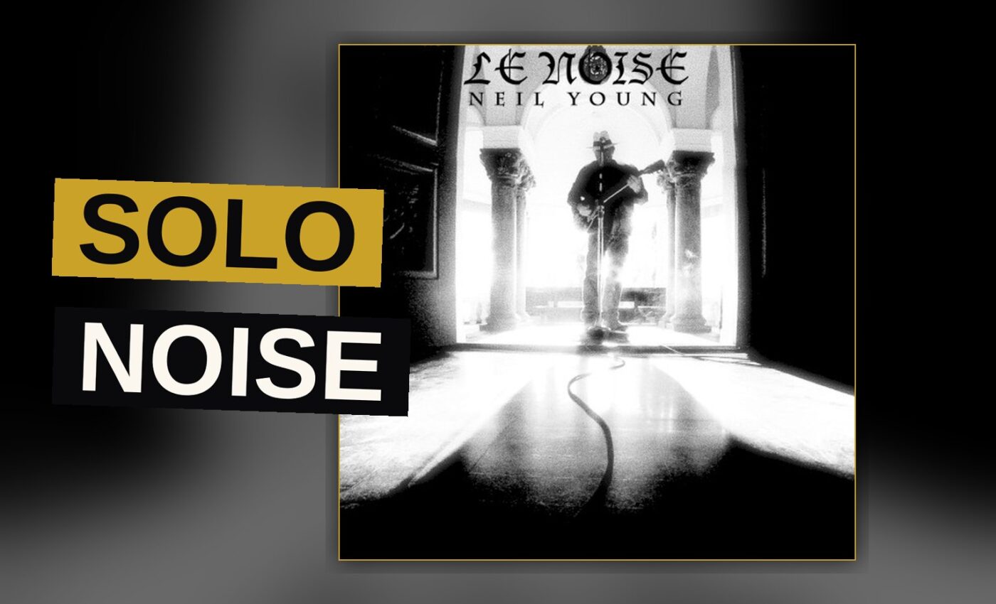 A solitary electric guitar stands in a dim, echoing room, its haunted stillness filling the frame.