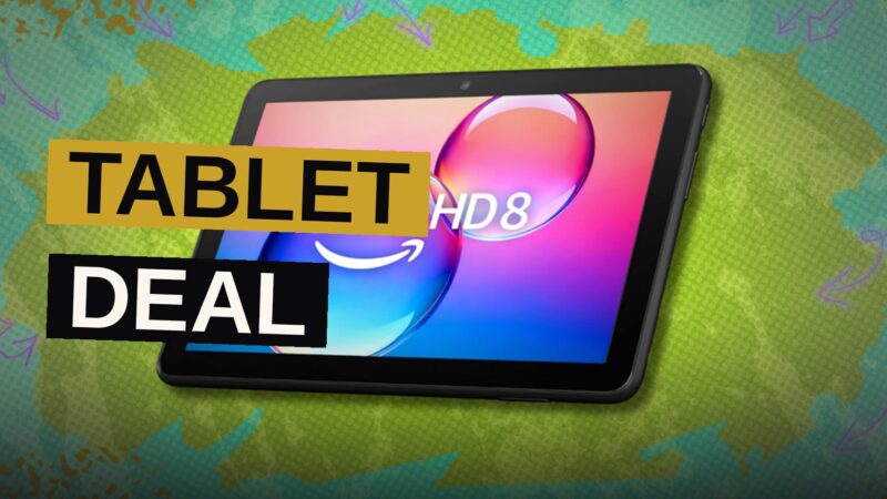 A black Amazon Fire HD 8 tablet displaying colorful apps on its screen, resting on a modern desk.