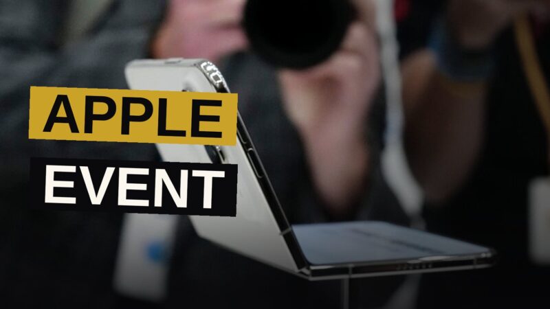 A foldable smartphone half-open on a dark stage with spotlights and bokeh, evoking a high-tech keynote.