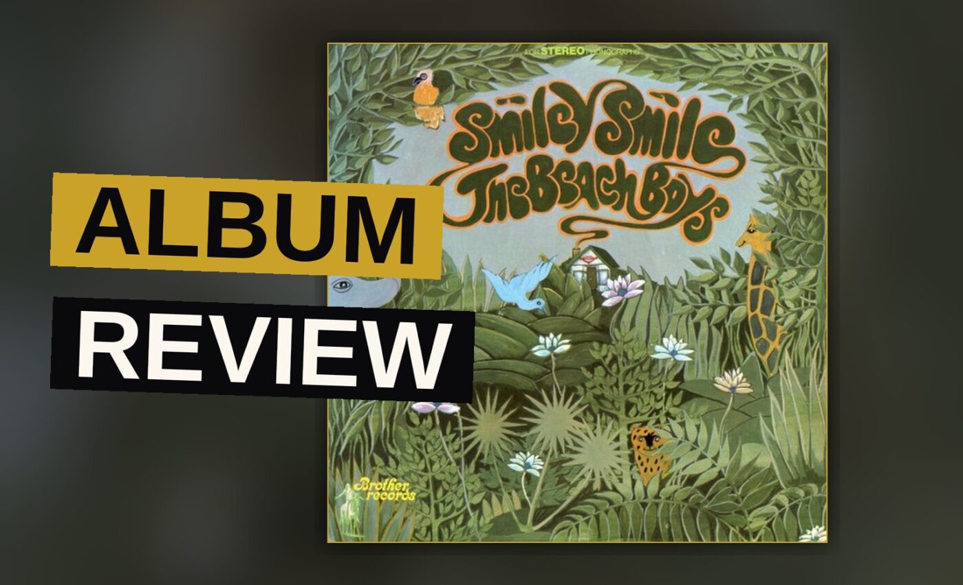 A vintage vinyl record sleeve for Smiley Smile rests on a wooden table in soft light.