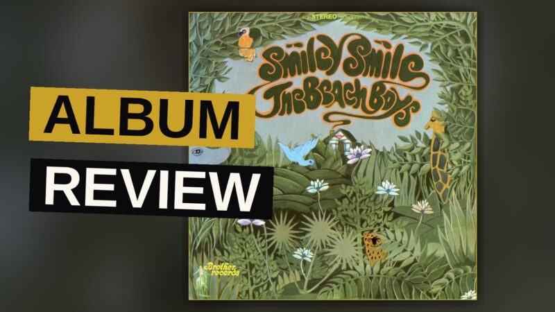 A vintage vinyl record sleeve for Smiley Smile rests on a wooden table in soft light.