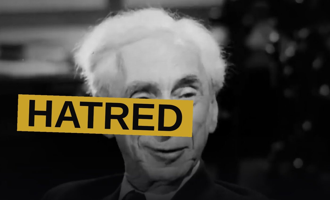 An aged philosopher, seated before old cameras, speaks with grave conviction upon a shadowed stage.