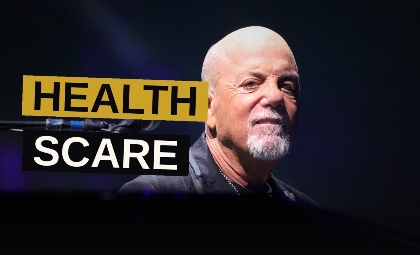 Billy Joel sits alone backstage in a dimly lit room, looking thoughtful and concerned.
