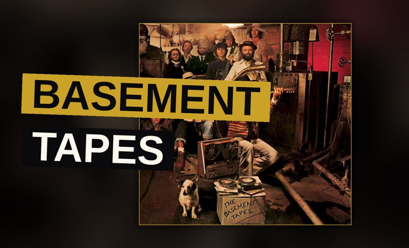Two musicians play instruments in a dim, cluttered basement, evoking the informal vibe of the Basement Tapes sessions.