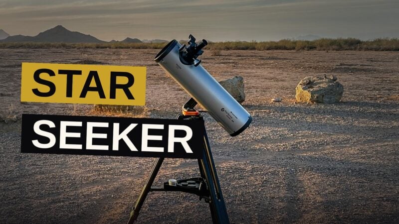 A portable telescope sits on a tripod under a starry night sky, guided by a smartphone.