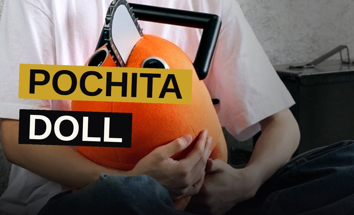 A life-size orange Pochita doll with a chainsaw blade sits posed on a wooden floor in a bright room.