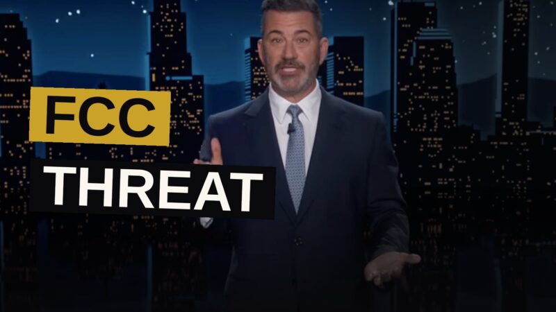 A late-night talk show desk with a microphone, with a screen displaying the YouTube logo in the background.