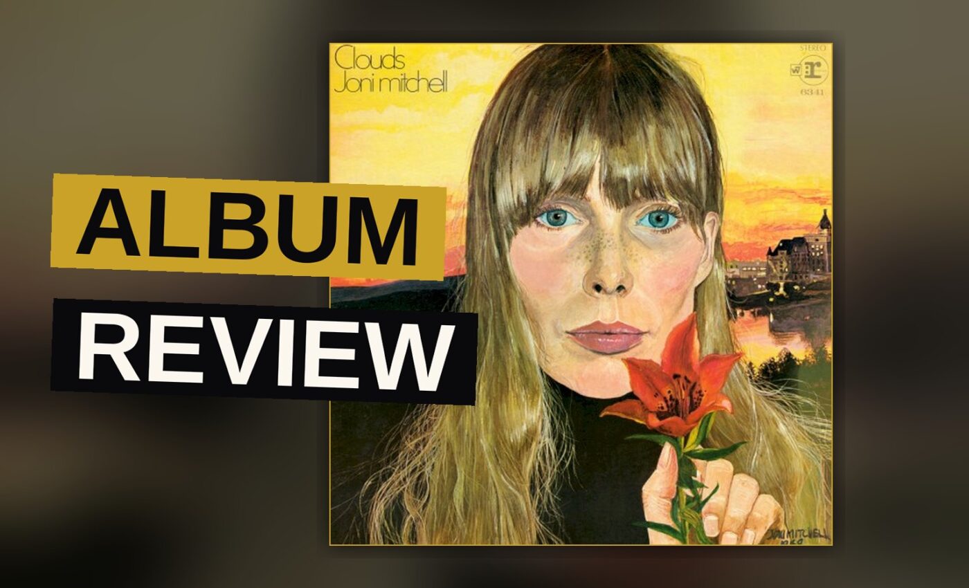 A vintage vinyl record sleeve for Joni Mitchell's 'Clouds' album resting on a wooden table with a guitar nearby.