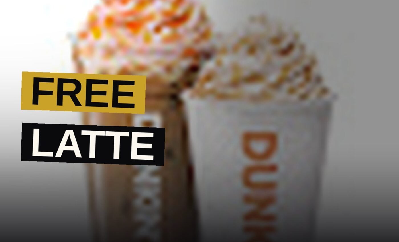 A medium pumpkin spice latte, crowned with whipped cream and cinnamon sugar, rests upon a counter within a warm autumnal establishment.