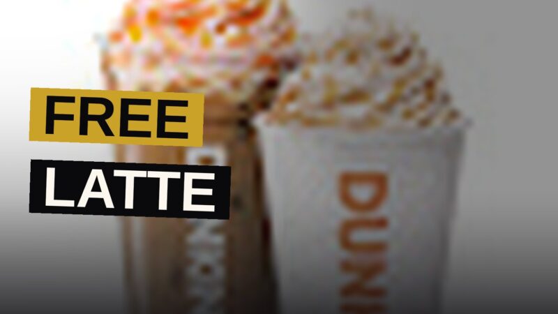 A medium pumpkin spice latte, crowned with whipped cream and cinnamon sugar, rests upon a counter within a warm autumnal establishment.