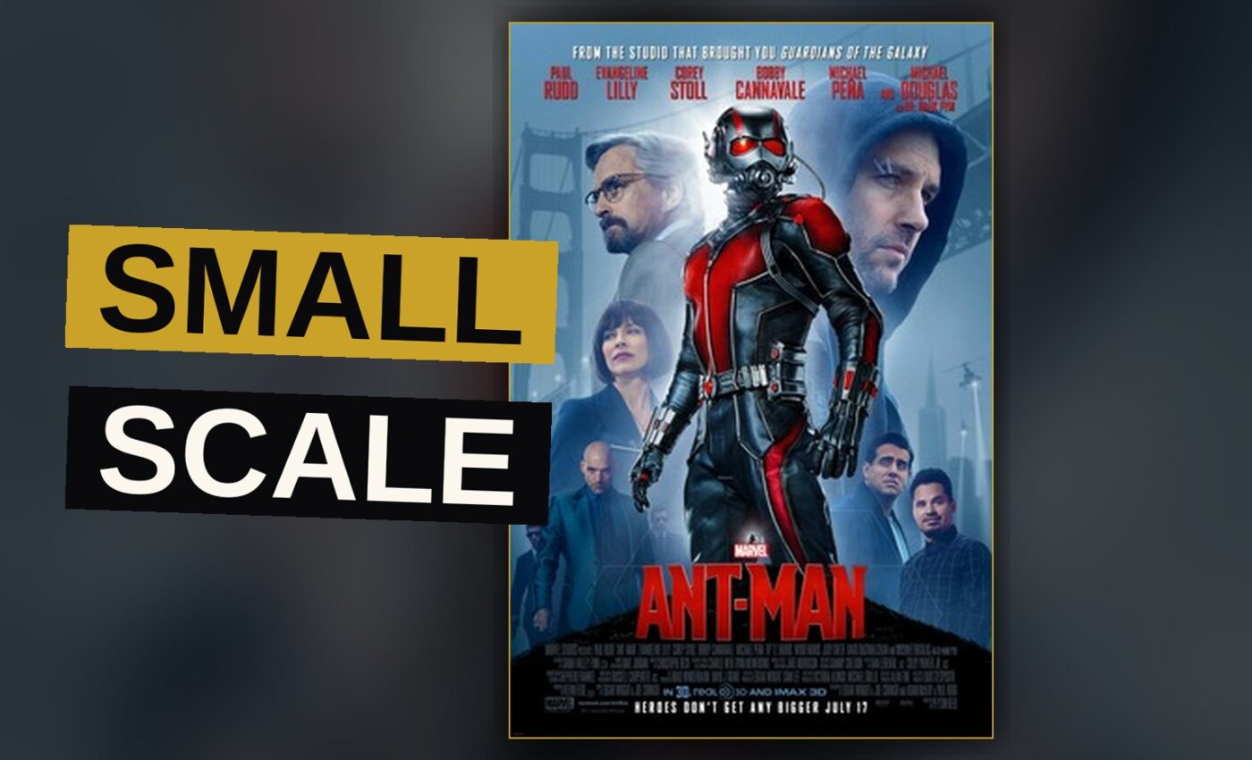 Ant-Man in his suit stands on a model train track, facing a toy train engine in a child's bedroom.