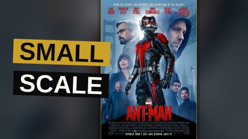 Ant-Man in his suit stands on a model train track, facing a toy train engine in a child's bedroom.