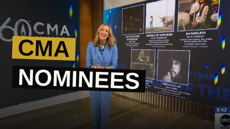 A country music award ceremony stage with golden lights and a large screen showing the 60th CMA Awards logo.