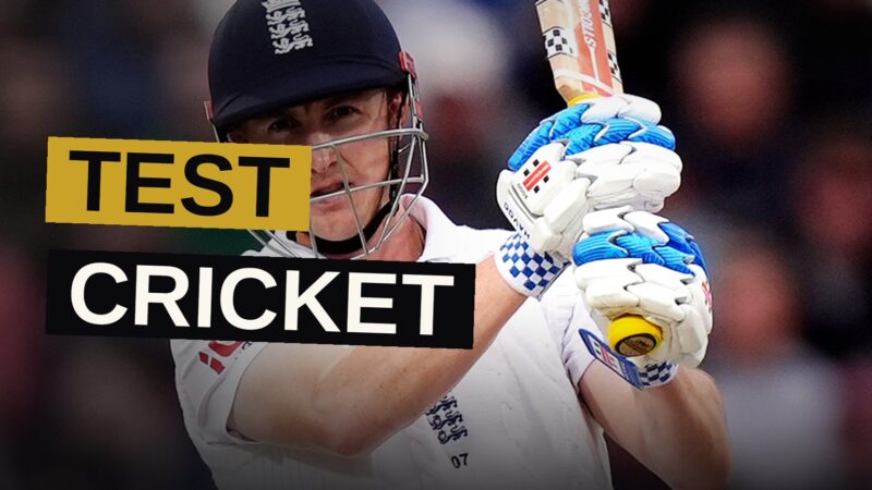 Cricketers in white play at Edgbaston stadium with a lively crowd watching.
