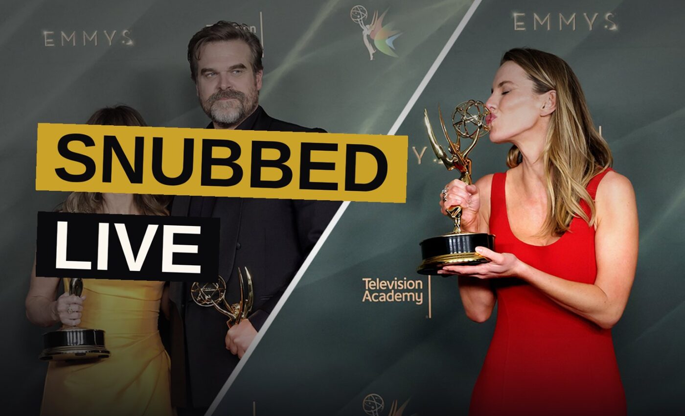 An Emmy award statuette glows under backstage lighting as a crowd blurs in the distance.