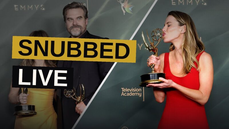 An Emmy award statuette glows under backstage lighting as a crowd blurs in the distance.