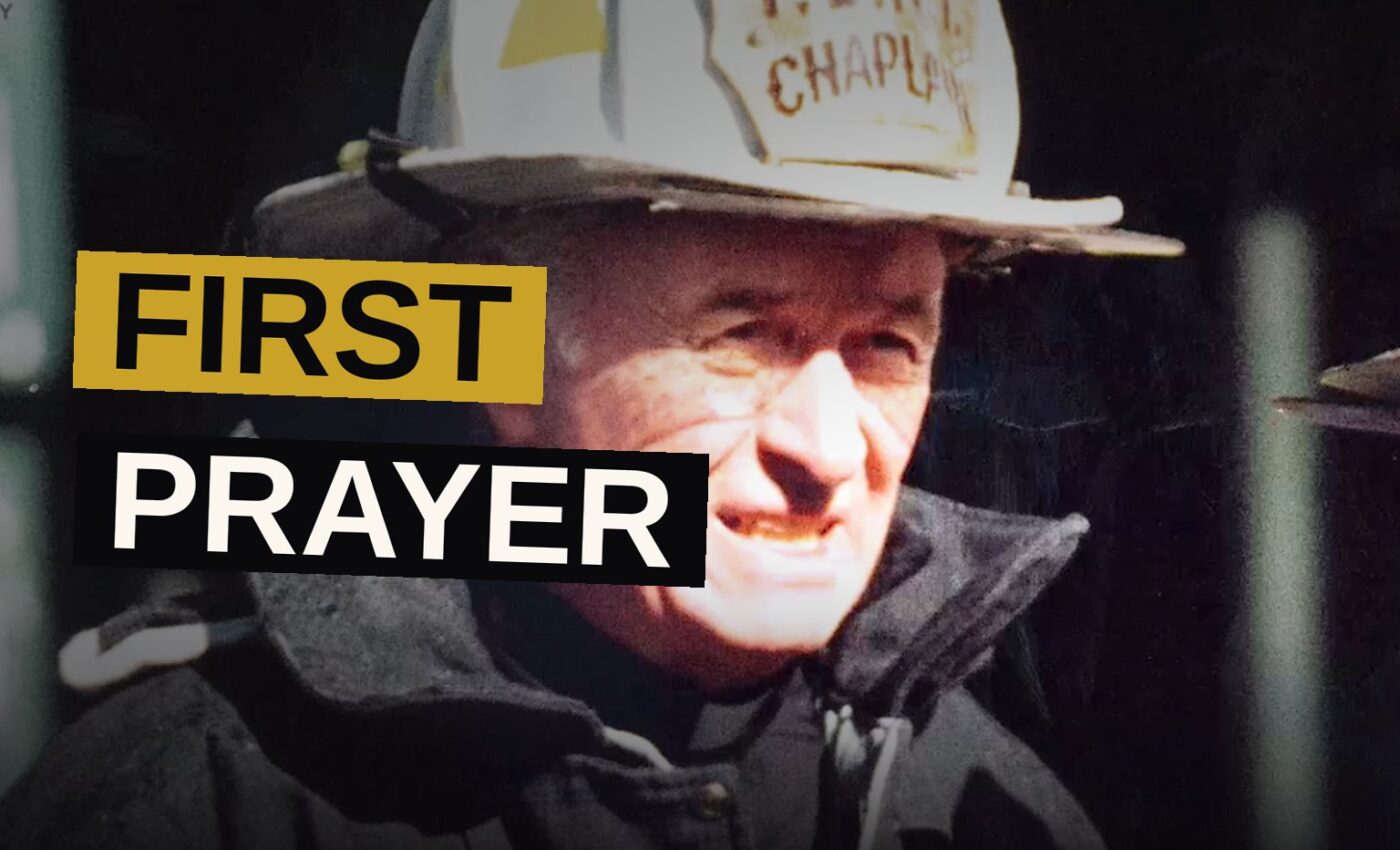 A weary firefighter carries the body of a priest amid the ruins of a smoldering tower.