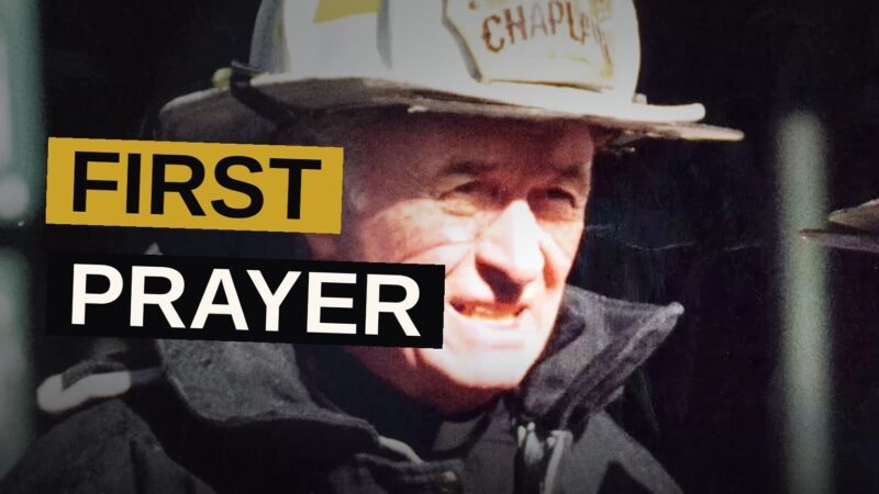 A weary firefighter carries the body of a priest amid the ruins of a smoldering tower.