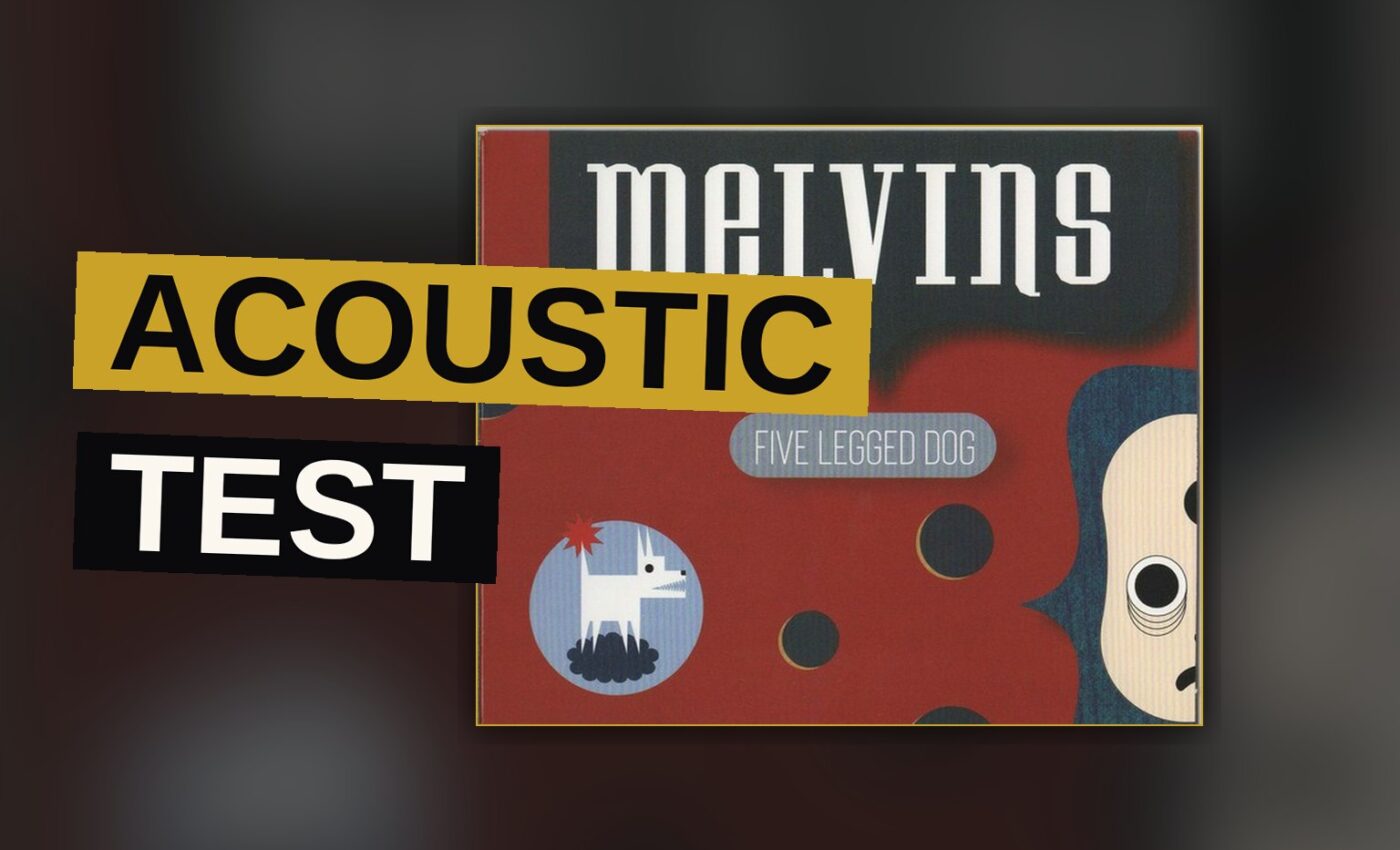 An acoustic guitar rests beside a silent amplifier in a dim chamber, awaiting the next song.