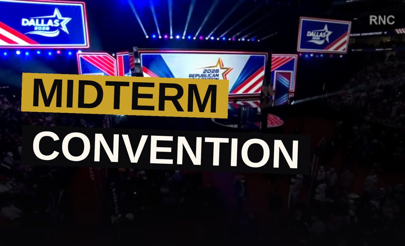 A large convention hall in Dallas with a red, white, and blue stage and a sparse audience.