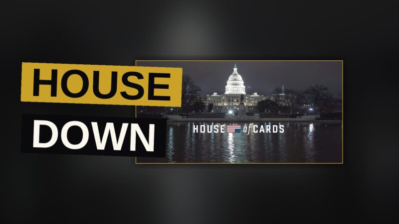 A dark-suited man stands before a shadowy Washington backdrop in a tense political scene.