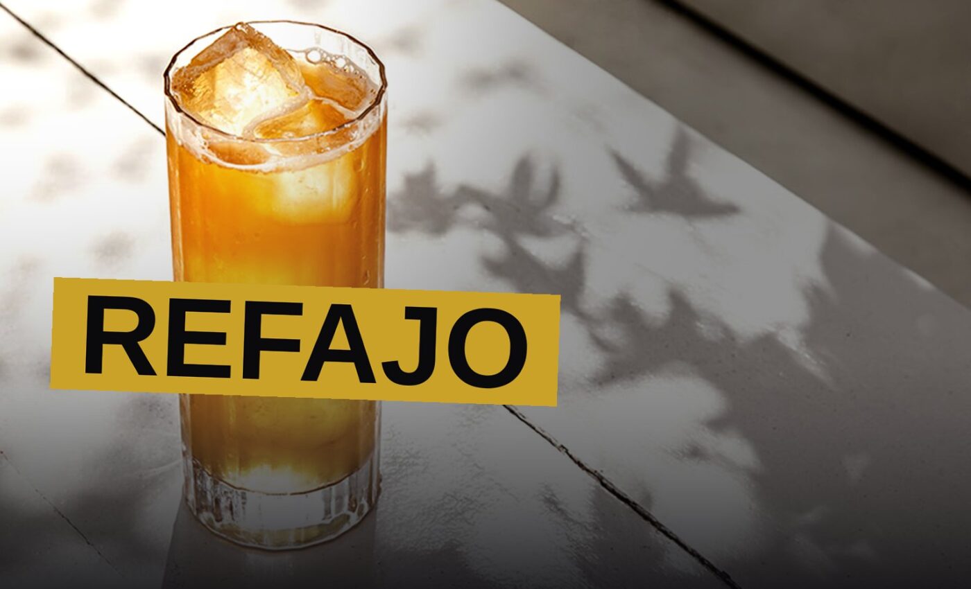 A pitcher of Refajo, a beer and soda shandy, sits on a table with tropical fruit slices in warm afternoon light.
