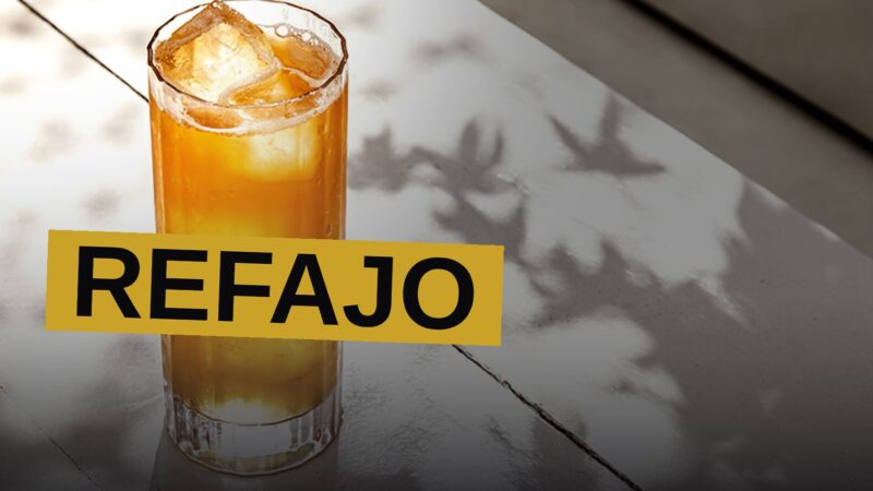 A pitcher of Refajo, a beer and soda shandy, sits on a table with tropical fruit slices in warm afternoon light.