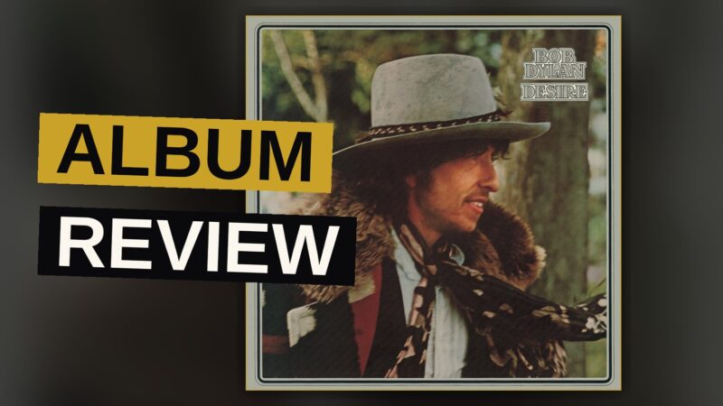 A man in a wide-brimmed hat stands in a smoky, dimly lit room with a violin nearby, evoking a 1970s album cover.
