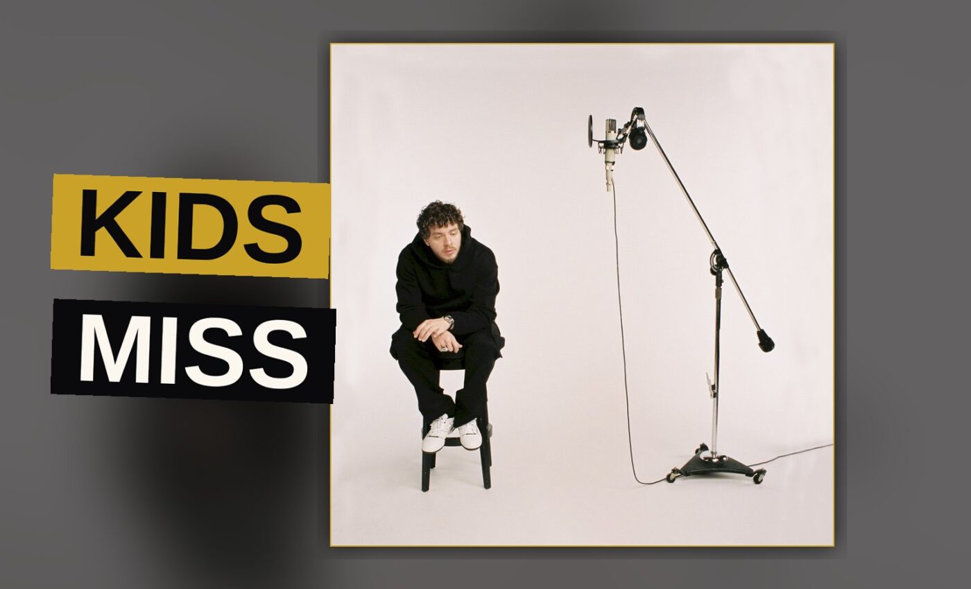 A rapper stands amid dim light and shadow, a solitary figure weighed down by the weight of fatherhood and fame.