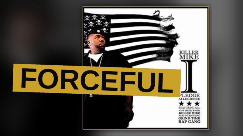 A rapper stands under bright light, his face tense and determined.