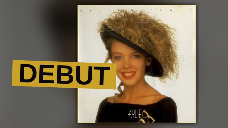 A young singer stands amid bright lights, recalling the record's bright, radio-friendly sound.