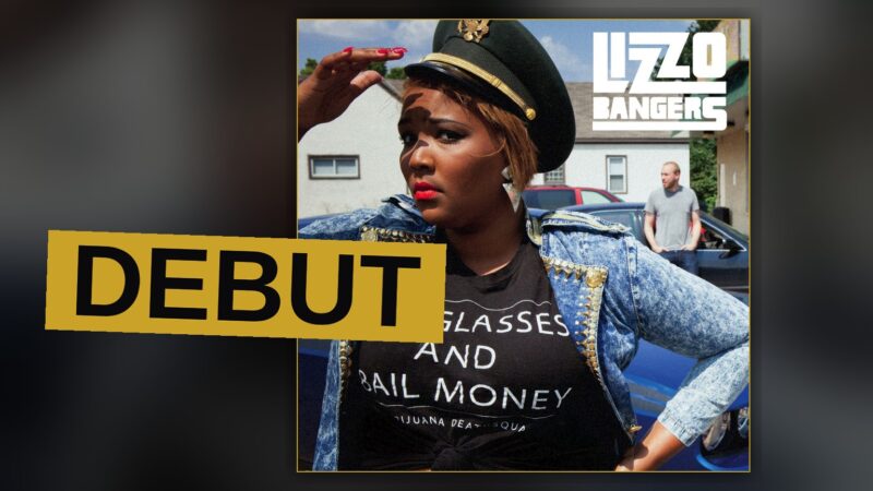 A confident young rapper stands bathed in stage light, exuding energy and personality.