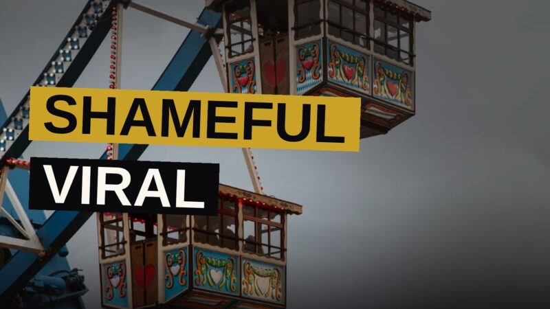 A ferris wheel glows at night while a crowd gathers below, a scene of public spectacle and shame.