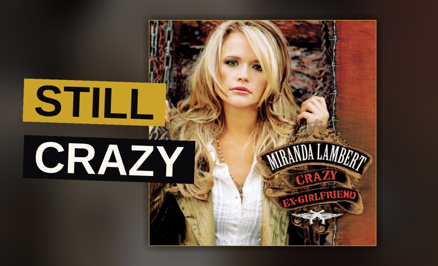 A female country singer performs energetically on a dark stage lit with red and blue lights.