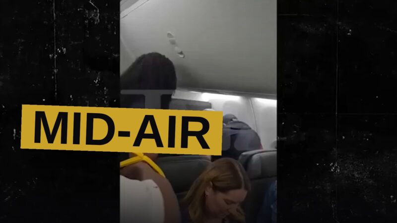 Two men hold down a raving passenger in his seat while others look on in dread within the narrow cabin.