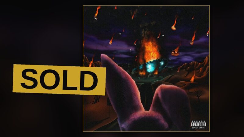 A rapper stands amid smoke and golden light, jewelry catching the glow, in a portrait fit for a costly record.