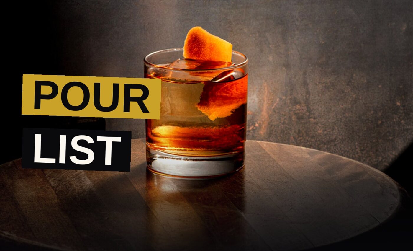Six whiskey cocktails in different glasses arranged on a wooden bar top, with warm amber lighting and subtle shadows.