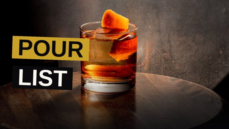 Six whiskey cocktails in different glasses arranged on a wooden bar top, with warm amber lighting and subtle shadows.