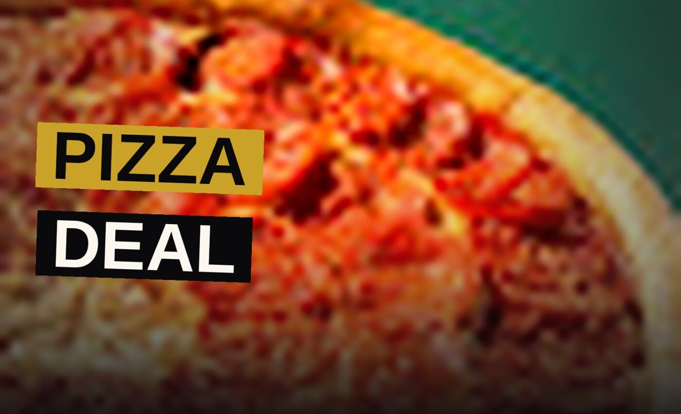A large pepperoni pizza with extra pepperoni and herbs on a wooden table.