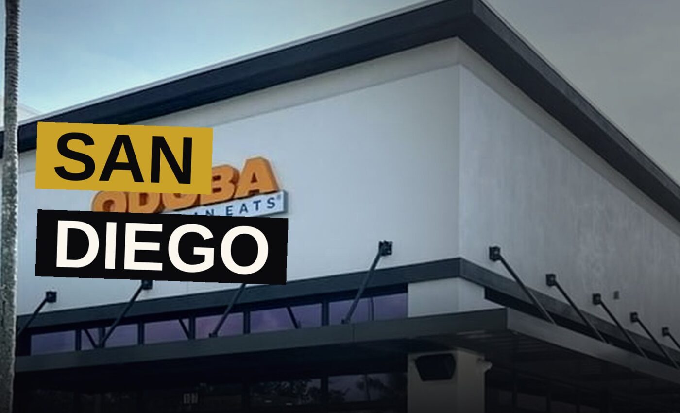 A Qdoba Mexican Eats restaurant with its sign lit up at dusk.