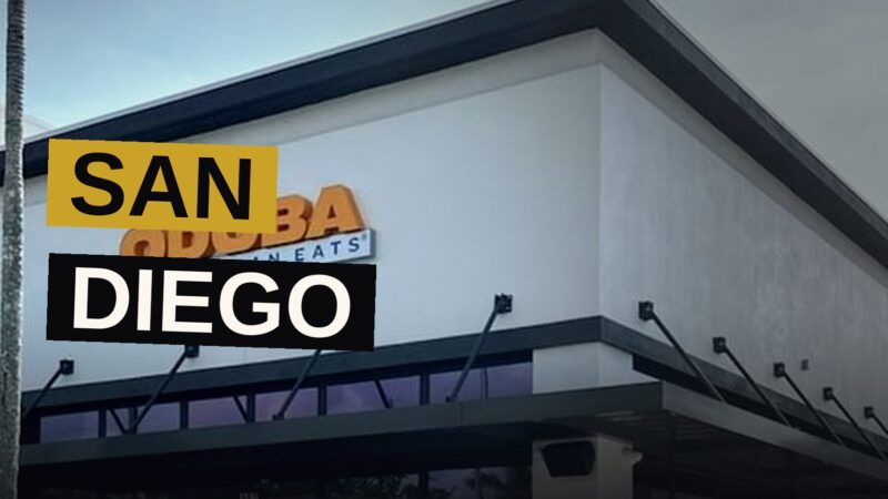 A Qdoba Mexican Eats restaurant with its sign lit up at dusk.