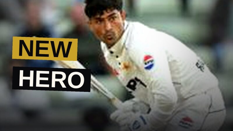 A young batter raises his bat in triumph as a vast crowd watches in astonishment.