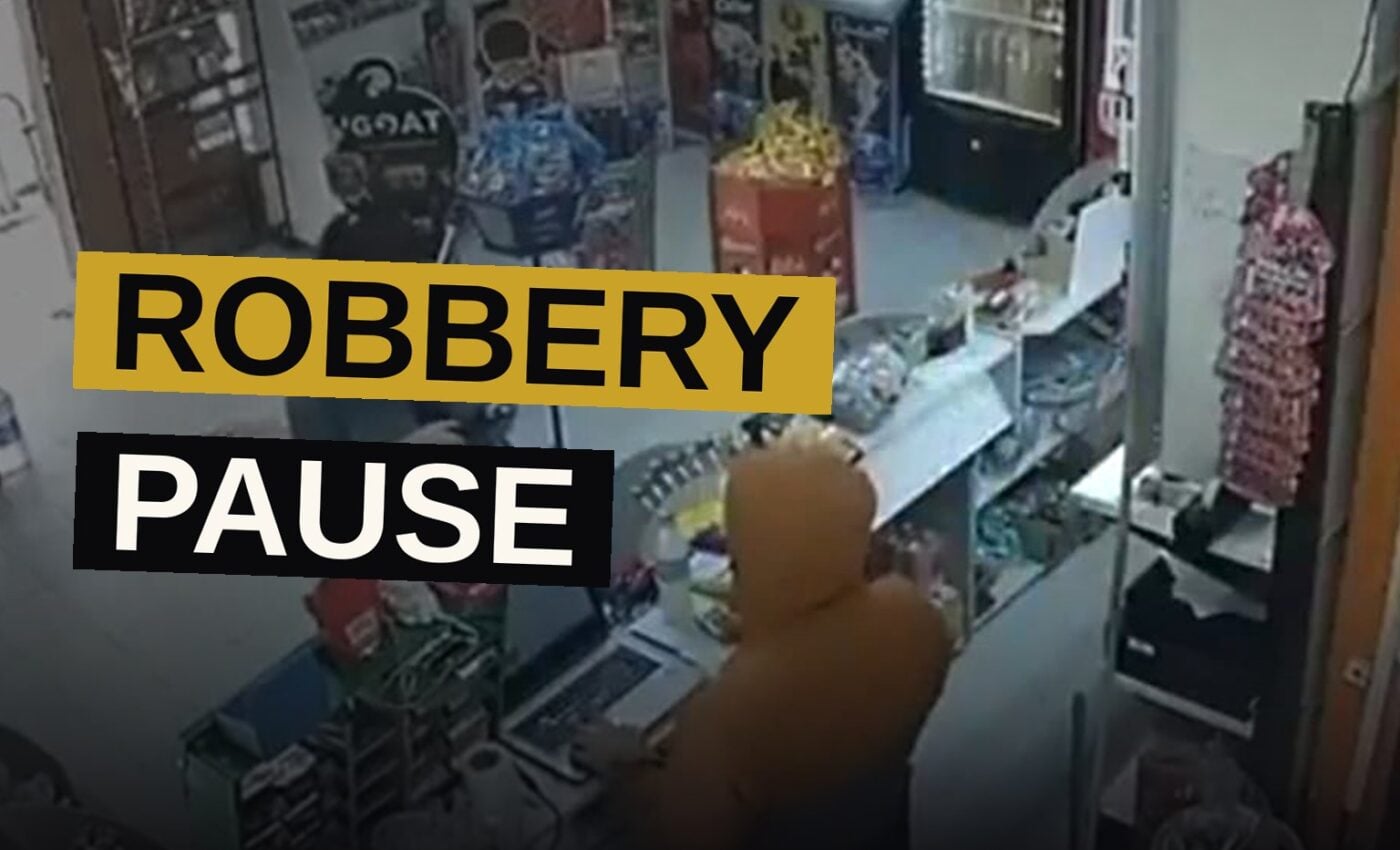 A hooded man in a store hands a receipt to a customer while another hooded figure stands by the entrance, in a CCTV-style image.