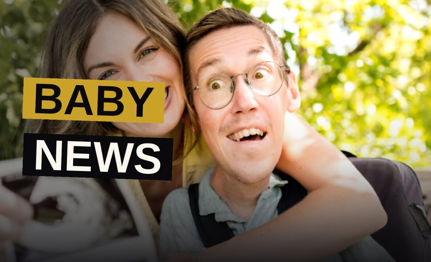 Shane and Hannah Burcaw smile together at home, Hannah cradling her baby bump, their dog nearby.