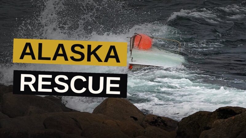 A Coast Guard helicopter hovers over an overturned boat in Alaska waters while a teen clings to the hull.