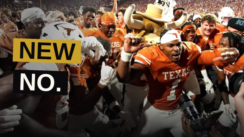 A college football player scores a touchdown under bright stadium lights as fans react.